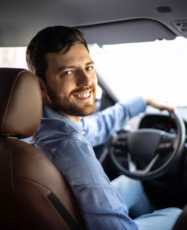 Uśmiechnięty mężczyzna za kierownicą pojazdu